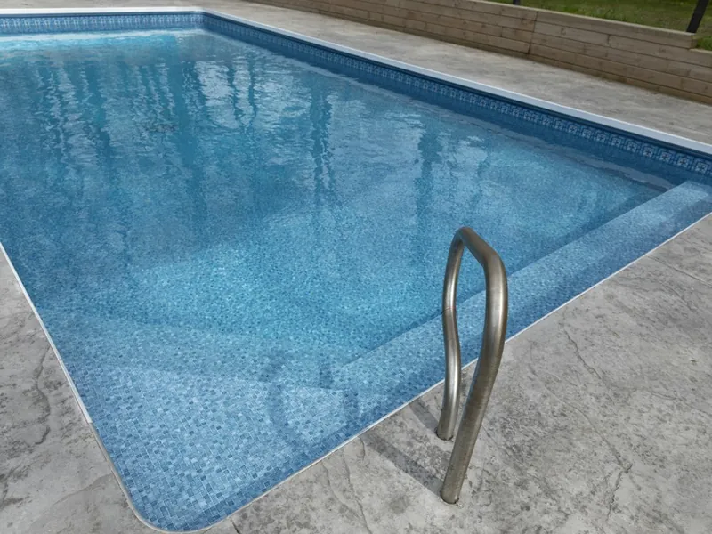 Clean blue pool with a stamped concrete deck and stainless ladder in Vista